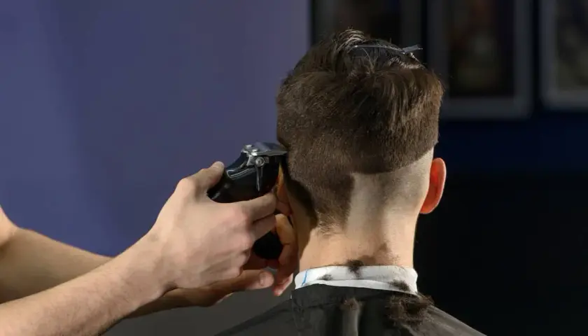 Friseur schneidet mit Maschine einen **mid fade** Haarschnitt.