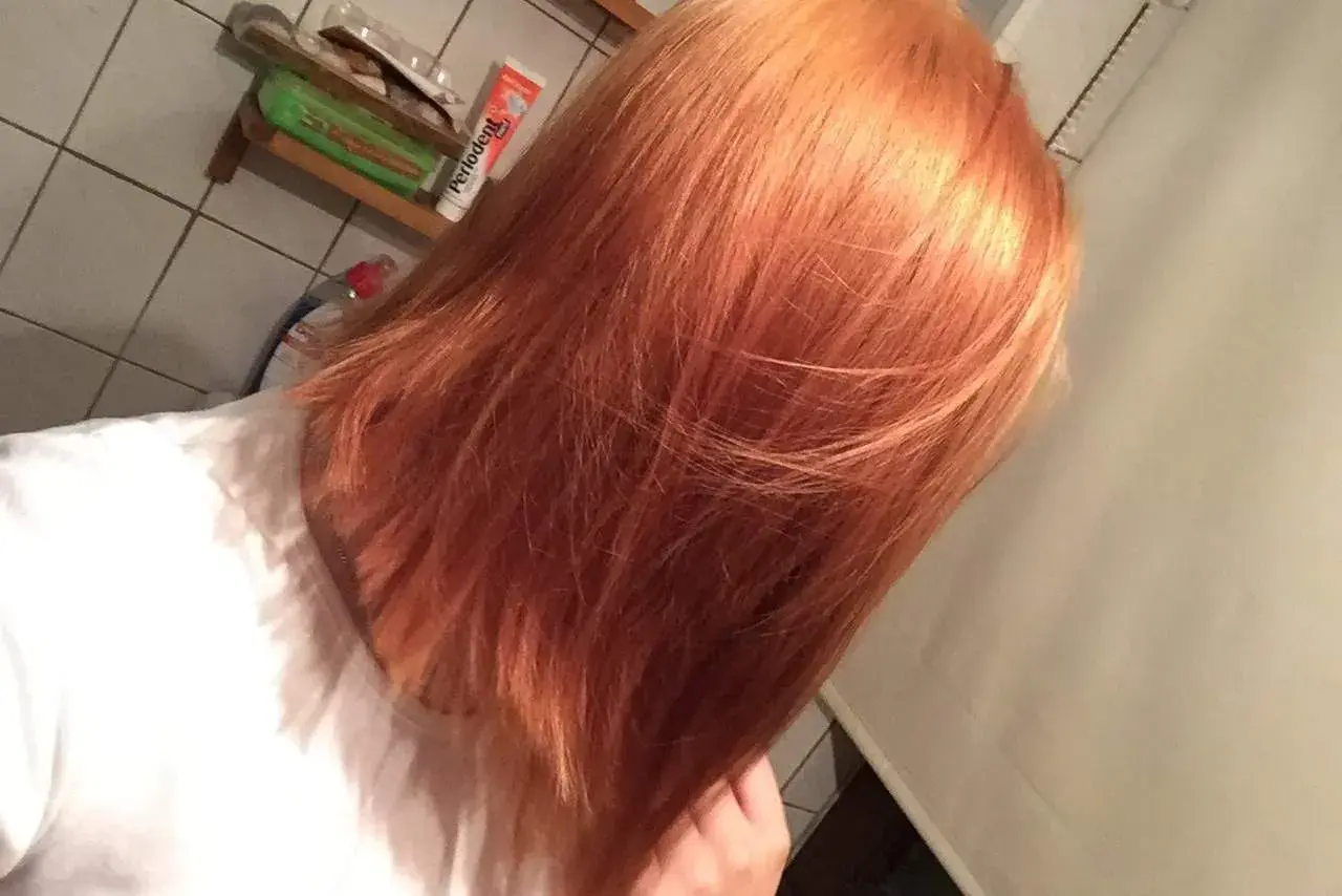 Orange Haare, bereit, nochmal blondiert zu werden. Ein Blick in den Spiegel vor dem nächsten Schritt.