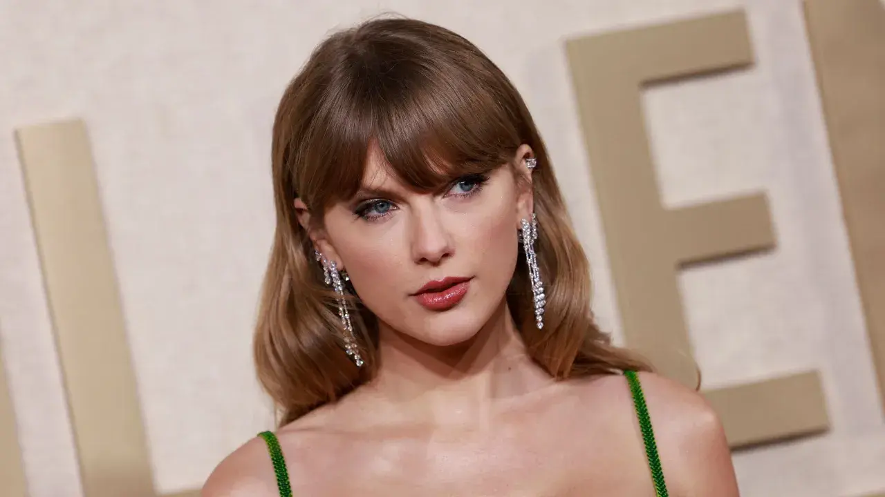 Taylor Swift mit ihrer charakteristischen hellbraunen taylor swift haarfarbe, funkelnden Ohrringen und einem grünen Kleid.
