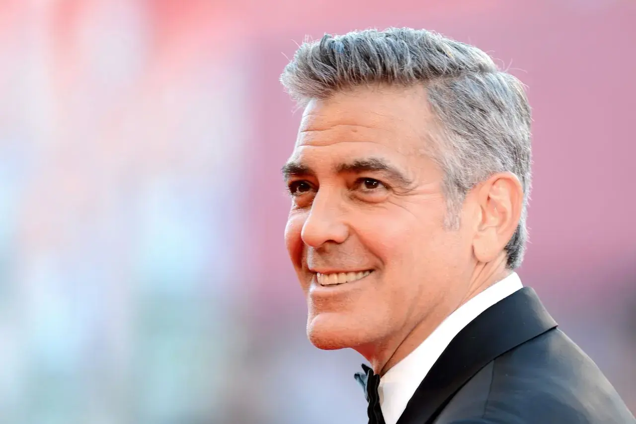 George Clooney zeigt eine stilvolle Frisur für Herren ab 60 Jahren, mit grauem Haar und einem charmanten Lächeln.