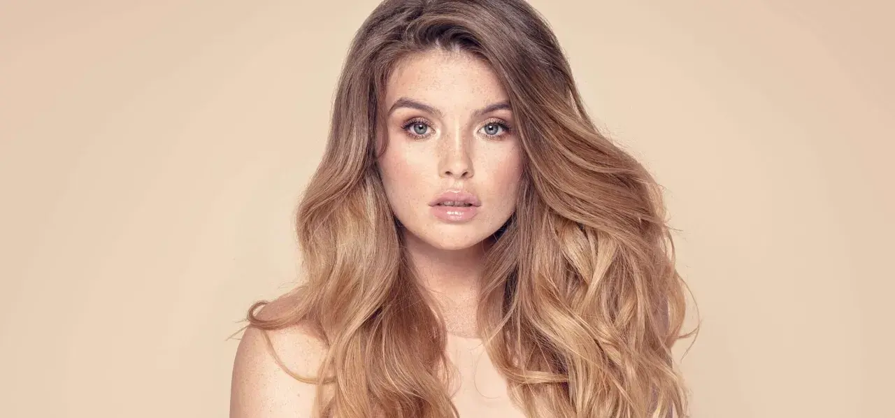 Frau mit vollem, welligem Haar und Sommersprossen. Sie träumt davon, dickere Haare zu bekommen, um diesen Look zu erzielen.