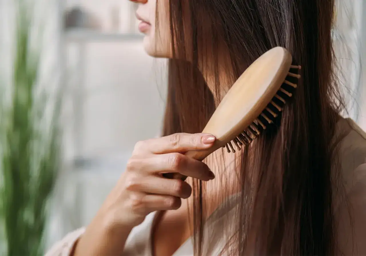 Frau kämmt ihr langes Haar. Sie hofft, dass dies gegen ihren extremen Haarausfall hilft.