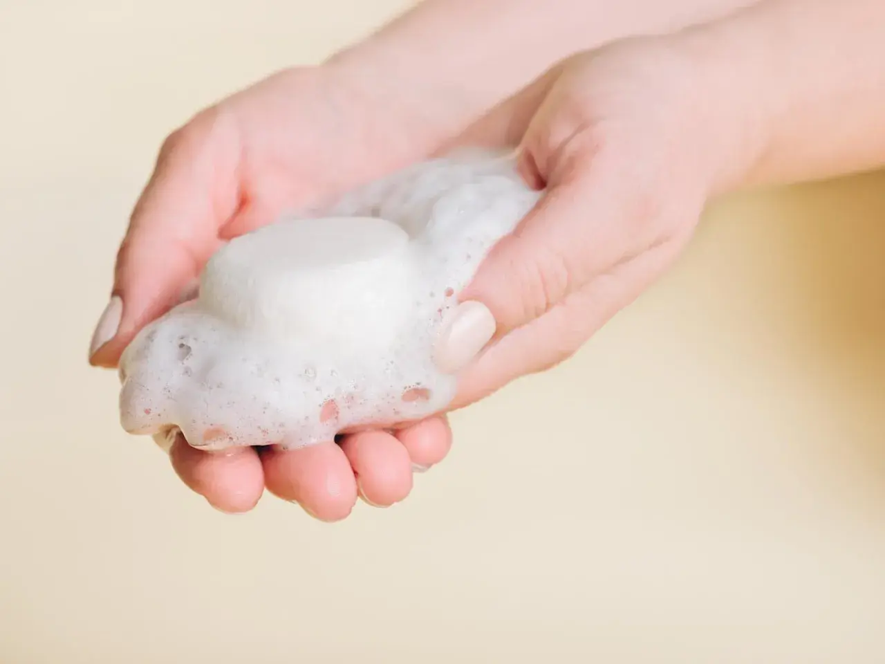 Hände halten festes Shampoo und Schaum. So einfach ist es, wie man festes Shampoo benutzt.