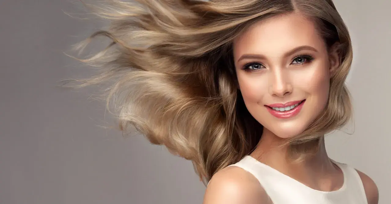 Ein Lächeln, das durch warmes blondes Haar umrahmt wird, das im Wind weht.