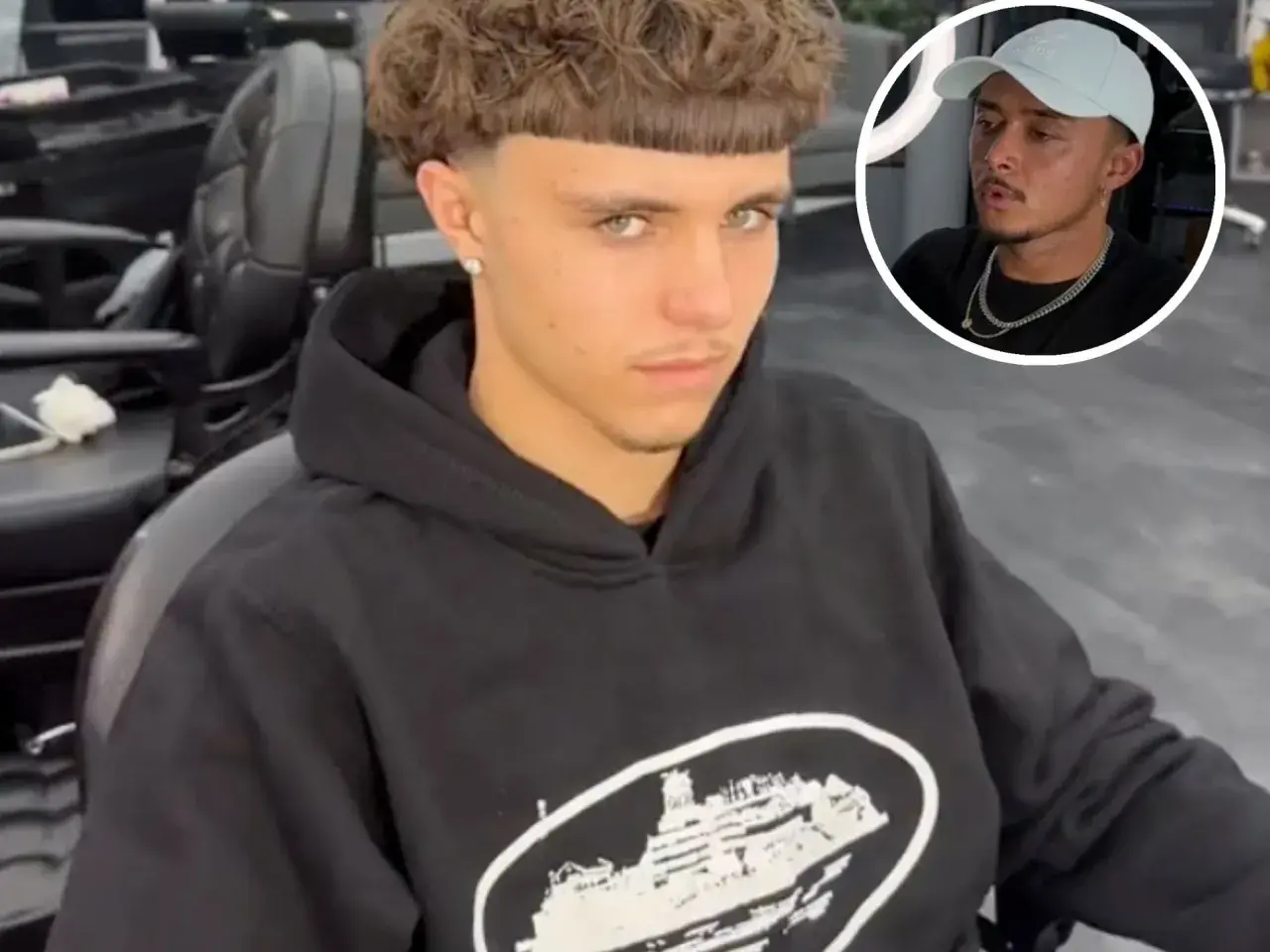 Junger Mann mit einem markanten Edgar Cut und einem lässigen Hoodie sitzt im Friseursalon. Im Kreis ist ein Mann mit Kappe zu sehen.