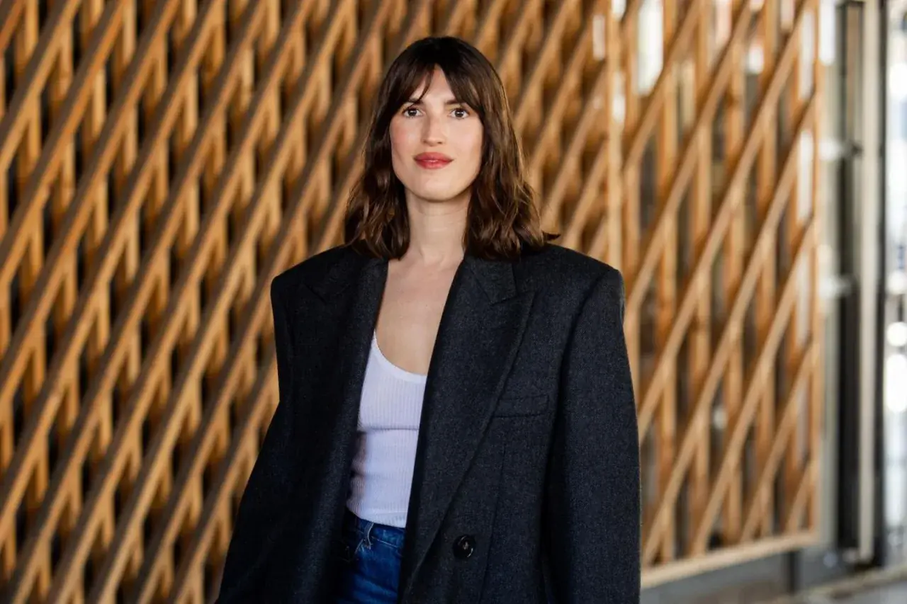 Frau mit braunem Haar und einem lässigen french crop, trägt einen Oversized-Blazer über einem weißen Top.