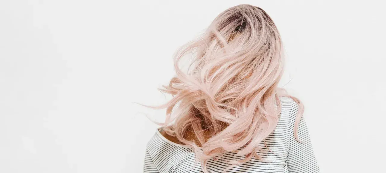 Eine Person mit langen, welligen, rosafarbenen Haaren. Die Haarfarben mischen Tabelle könnte hier inspirieren.