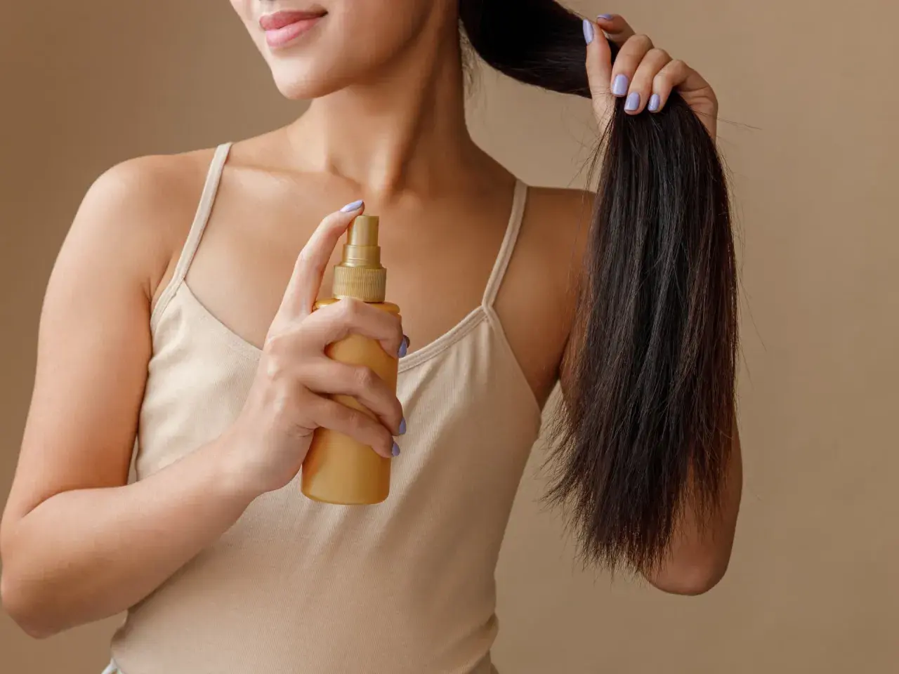 Frau sprüht sich Rosmarinwasser auf die Haare für mehr Glanz und Pflege.