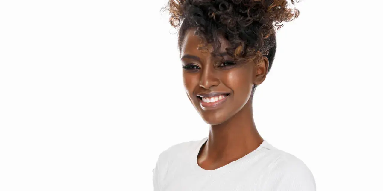 Lächelnde Frau mit voluminösen Locken, die sich für den perfekten Look Zeit nimmt, um Locken zu machen.