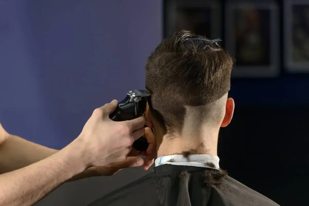 Friseur schneidet mit Maschine einen **mid fade** Haarschnitt.