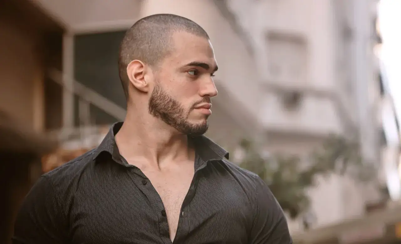 Mann mit Buzzcut und dezenten Geheimratsecken, blickt nach rechts.
