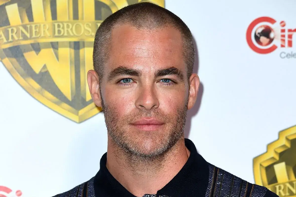 Ein Mann mit Geheimratsecken und blauen Augen blickt in die Kamera. Im Hintergrund sind Logos von Warner Bros. und CinemaCon zu sehen.