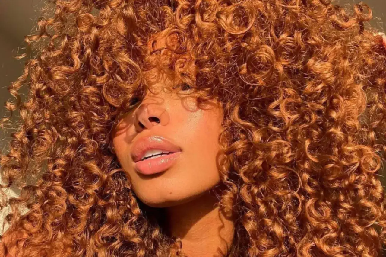 Kupferfarbene, natürliche Locken in einem Stufenschnitt, der Volumen und Bewegung verleiht. Diese Frisuren betonen die Textur und den Glanz der Haare.