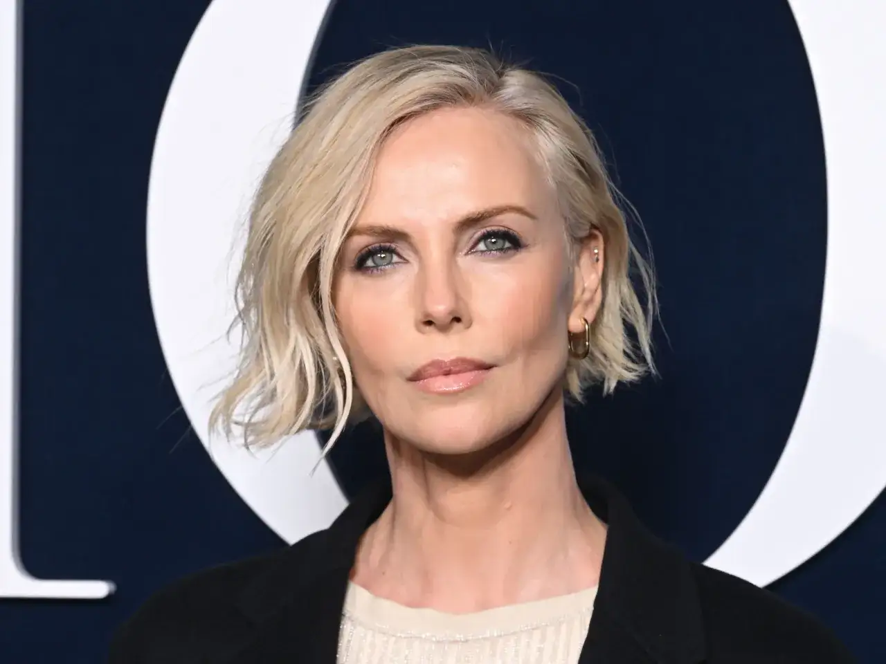 Blonde Frau mit mittellangen, gewellten Haaren, die eine elegante Frisur für Frauen ab 50 darstellt.