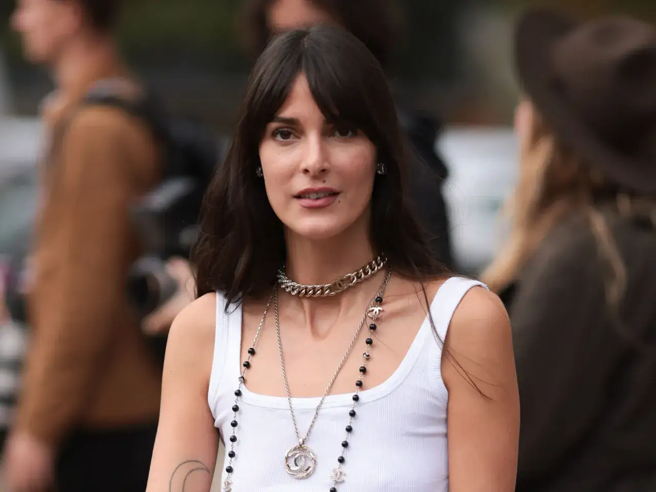 Frau mit langem Bob und Curtain Bangs, glatte Haare, trägt Chanel-Schmuck.