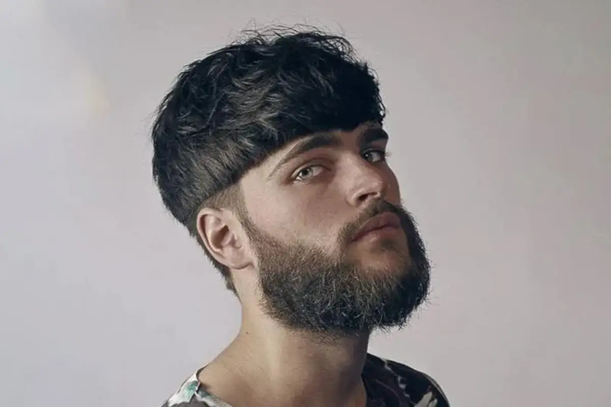 Junger Mann mit markantem Bowl Cut und Bart.