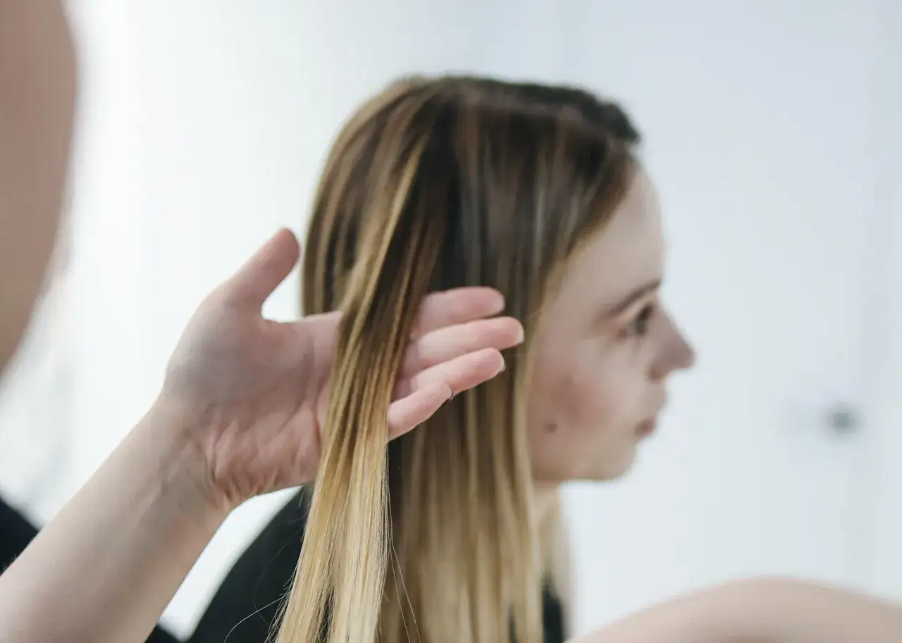 Hilfe bei Haare brechen am Ansatz ab: Eine Hand prüft die Spitzen einer blonden Frau.