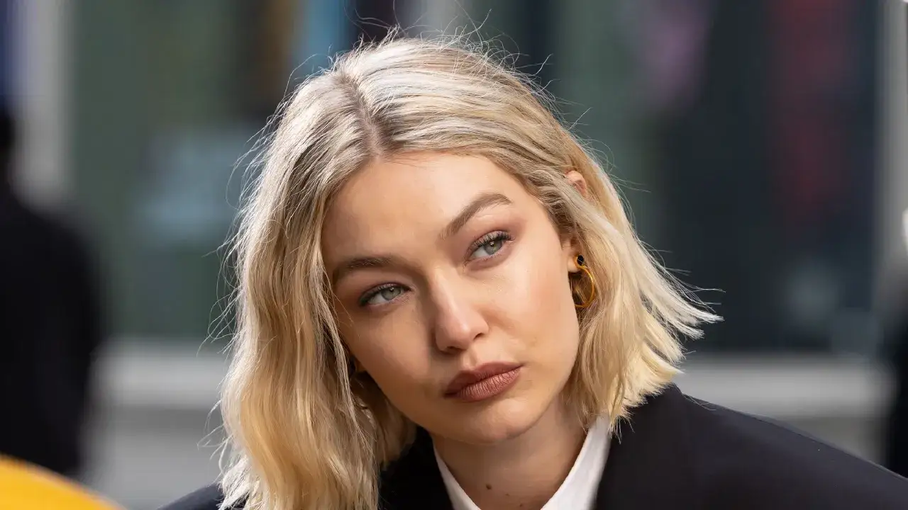 Blonde Frau mit einem langen Bob-Haarschnitt, die nachdenklich zur Seite blickt.