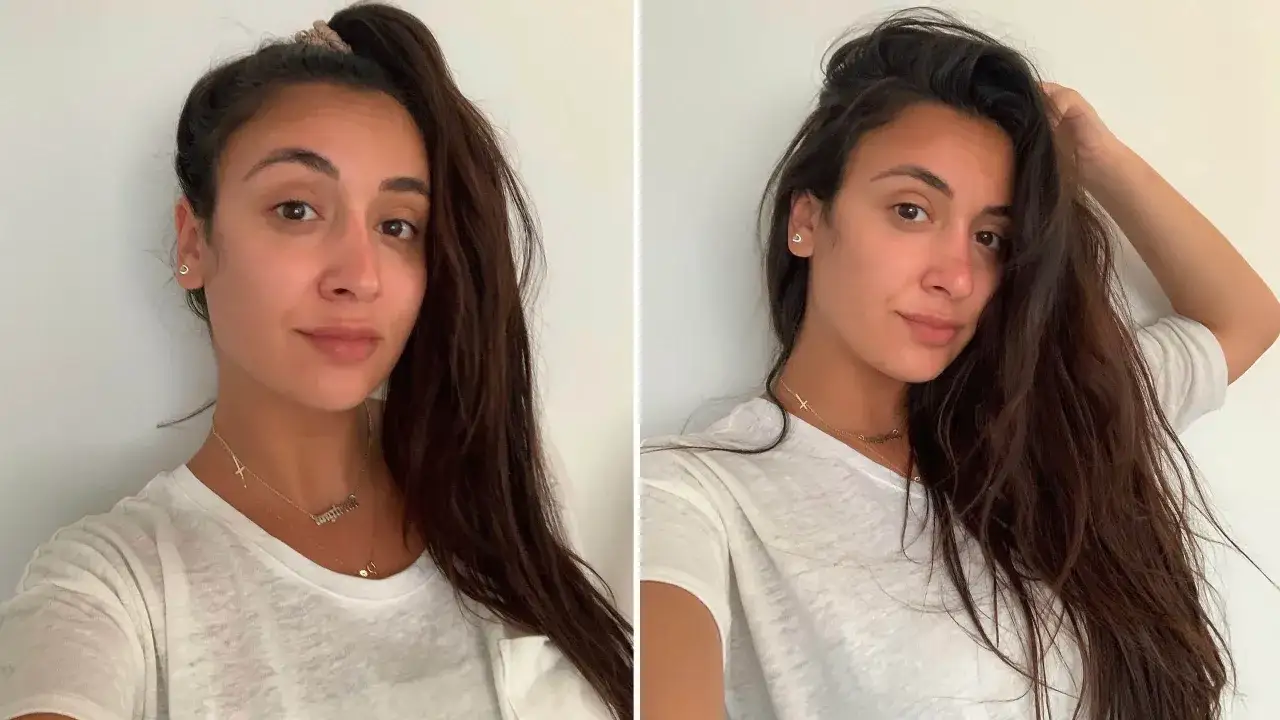 Frau mit dunklem Haar, die sich über ihr volles Haar freut. Sie hat ein Lächeln im Gesicht und trägt eine weiße Bluse.