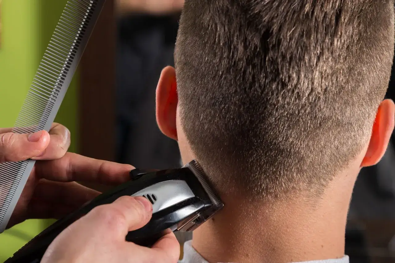 Pr&auml;zise Konturen Haare werden mit einem Trimmer und Kamm am Hinterkopf eines Mannes nachgearbeitet.