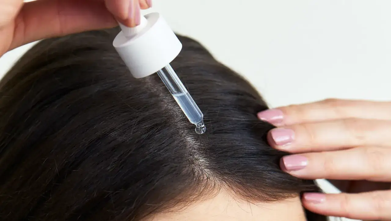 Eine Pipette gibt Serum auf die Kopfhaut, um normales Haar zu pflegen.