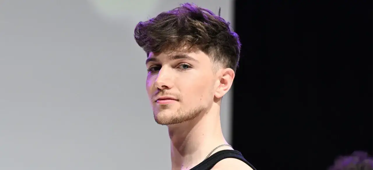 Junger Mann mit einem modernen taper fade cut, der nach vorne gestylt ist.