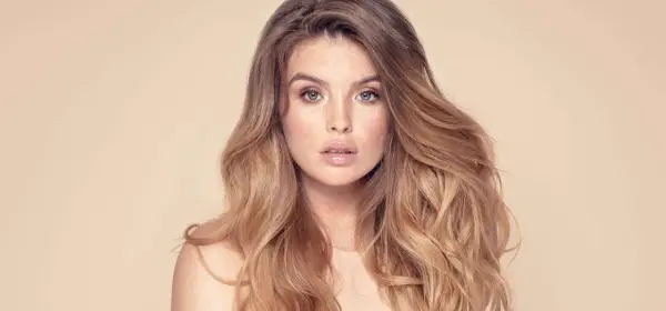 Frau mit vollem, welligem Haar und Sommersprossen. Sie träumt davon, dickere Haare zu bekommen, um diesen Look zu erzielen.